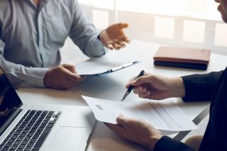 Foto: Personen besprechen Akten